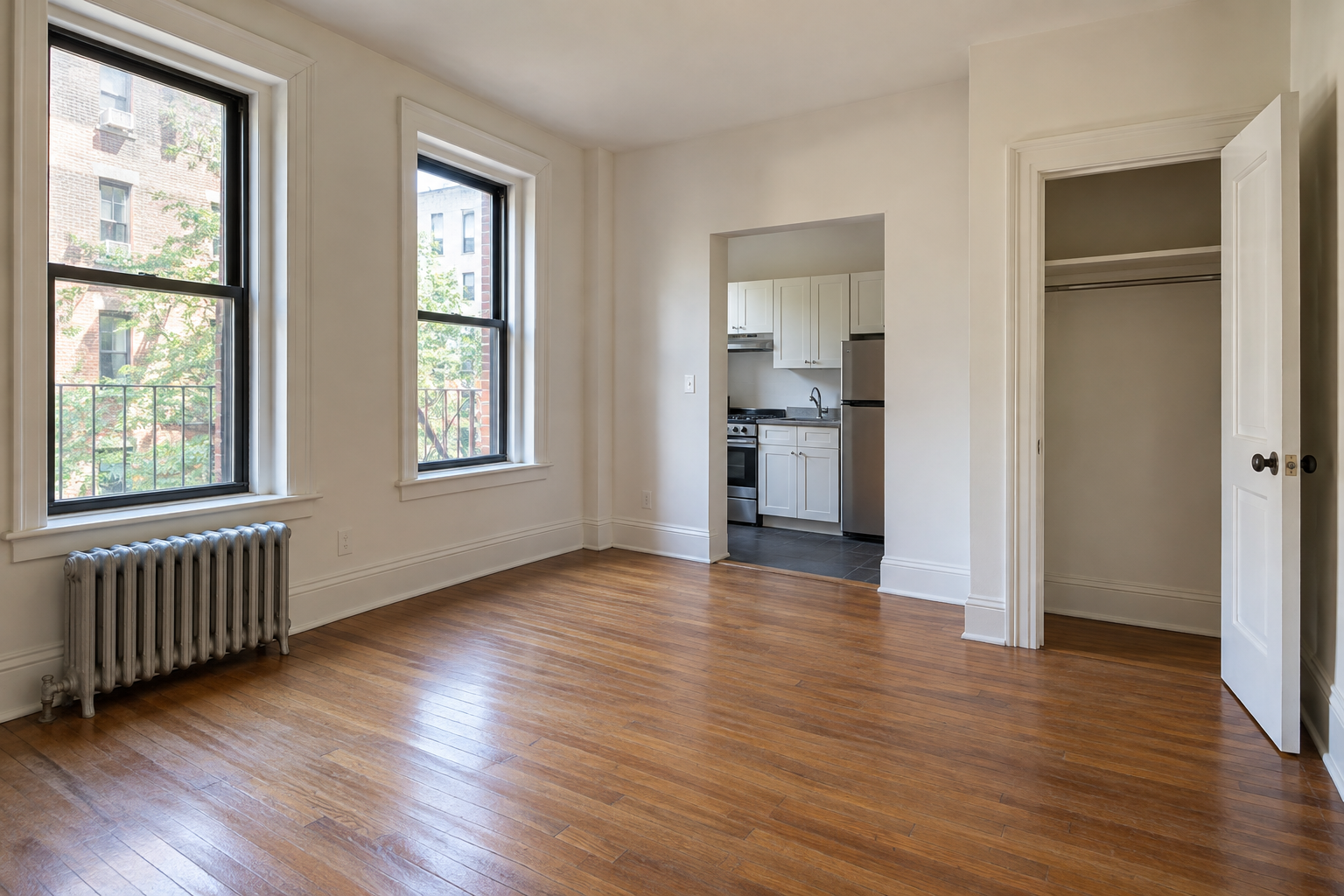 Unfurnished apartment living room with empty closet and compact kitchen visible in daylight